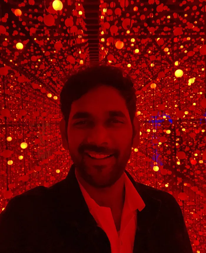 Banu smiling in a room of red lights